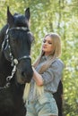 Beautiful brunette girl with long hair posing with a red horse in forest Royalty Free Stock Photo