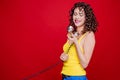 Beautiful brunette girl with makeup and curly hairstyle in casual style posing with a retro telephone receiver on a red background Royalty Free Stock Photo