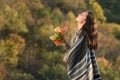 Beautiful brunette girl in a poncho holding a bouquet of autumn leaves and looking at the sky. Portrait Royalty Free Stock Photo