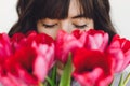 Beautiful brunette girl portrait with red tulips closeup on white background indoors, space for text. Stylish young woman Royalty Free Stock Photo