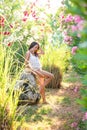 Beautiful brunette girl posing near a stone in a tropical garden with flowers Royalty Free Stock Photo