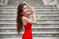 Beautiful brunette girl in red dress with long healthy hair posing on Staircase in Birth of our Lady Church, Montenegro Royalty Free Stock Photo