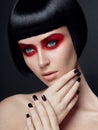 Beautiful brunette girl with red eye shadow and black bob hairstyle and nail. Closeup portrait of a model with makeup. Royalty Free Stock Photo