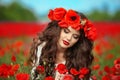 Beautiful brunette girl in red poppy flowers field nature background. Beauty outdoor portrait. Attractive young woman with red li Royalty Free Stock Photo