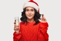 Beautiful brunette girl in a red sweater and Santa hat holding glass of champagne. Royalty Free Stock Photo