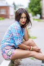 Beautiful brunette girl sitting on the road fashion lifestyle woman in colorful shirt
