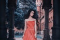 Beautiful brunette girl, with very long hair, in an orange, vintage dress