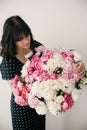 Beautiful brunette girl in vintage dress holding big bouquet with pink and white peonies. Happy stylish woman with peony flowers Royalty Free Stock Photo