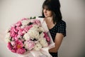 Beautiful brunette girl in vintage dress holding big bouquet with pink and white peonies. Happy stylish woman with peony flowers Royalty Free Stock Photo