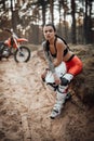 Beautiful girl wearing motocross outfit with semi naked torso sitting on a grass in the forest Royalty Free Stock Photo