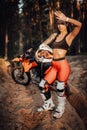 Beautiful brunette girl wearing motocross outfit with semi naked torso standing on a sand trail in the forest Royalty Free Stock Photo