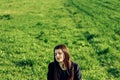 Beautiful brunette girl in windy green field, sunny springtime, Royalty Free Stock Photo