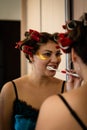 Beautiful brunette in home pajamas and curlers brushes her teeth near the mirror Royalty Free Stock Photo