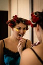 Beautiful brunette in home pajamas and curlers brushes her teeth near the mirror Royalty Free Stock Photo