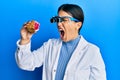 Beautiful brunette jeweller woman holding geode stone wearing magnifier glasses angry and mad screaming frustrated and furious,