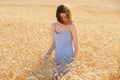 Beautiful brunette lady in blue dress walking in wheat field at sunset. Autumn portrait Royalty Free Stock Photo
