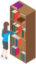 Beautiful brunette librarian woman in library chooses books on shelves in bookcase back view