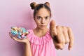 Beautiful brunette little girl holding jar full of sugar candies pointing with finger to the camera and to you, confident gesture Royalty Free Stock Photo