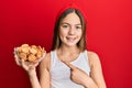 Beautiful brunette little girl holding salty biscuits in a bowl smiling happy pointing with hand and finger Royalty Free Stock Photo