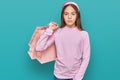 Beautiful brunette little girl holding shopping bags thinking attitude and sober expression looking self confident Royalty Free Stock Photo