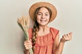 Beautiful brunette little girl holding spike wheat screaming proud, celebrating victory and success very excited with raised arm Royalty Free Stock Photo