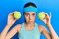 Beautiful brunette little girl holding tennis ball close to eyes depressed and worry for distress, crying angry and afraid Royalty Free Stock Photo