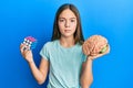 Beautiful brunette little girl playing colorful puzzle cube intelligence game and holding brain relaxed with serious expression on