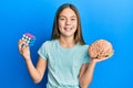 Beautiful brunette little girl playing colorful puzzle cube intelligence game and holding brain smiling and laughing hard out loud