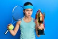 Beautiful brunette little girl playing tennis holding trophy clueless and confused expression Royalty Free Stock Photo