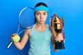 Beautiful brunette little girl playing tennis holding trophy depressed and worry for distress, crying angry and afraid Royalty Free Stock Photo