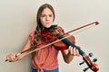 Beautiful brunette little girl playing violin skeptic and nervous, frowning upset because of problem Royalty Free Stock Photo