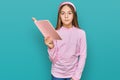 Beautiful brunette little girl reading a book thinking attitude and sober expression looking self confident Royalty Free Stock Photo