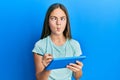 Beautiful brunette little girl using touchpad drawing on screen making fish face with mouth and squinting eyes, crazy and comical