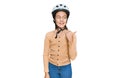 Beautiful brunette little girl wearing bike helmet smiling with happy face looking and pointing to the side with thumb up Royalty Free Stock Photo