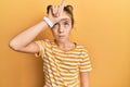 Beautiful brunette little girl wearing casual striped t shirt making fun of people with fingers on forehead doing loser gesture Royalty Free Stock Photo