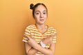 Beautiful brunette little girl wearing casual striped t shirt pointing to both sides with fingers, different direction disagree