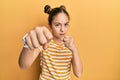 Beautiful brunette little girl wearing casual striped t shirt punching fist to fight, aggressive and angry attack, threat and Royalty Free Stock Photo