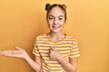 Beautiful brunette little girl wearing casual striped t shirt showing palm hand and doing ok gesture with thumbs up, smiling happy Royalty Free Stock Photo