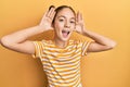 Beautiful brunette little girl wearing casual striped t shirt smiling cheerful playing peek a boo with hands showing face Royalty Free Stock Photo