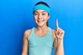 Beautiful brunette little girl wearing sportswear and diadem pointing finger up with successful idea Royalty Free Stock Photo