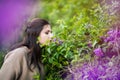 Beautiful brunette long haired 30 years old girl with fashionable makeup smells lilac in garden with closed eyes and enjoys of the Royalty Free Stock Photo