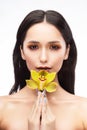 A beautiful brunette nude shoulders girl sensually holds a flower of an orchid in her hands. Nude make-up. Healthy smooth skin Royalty Free Stock Photo