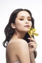 A beautiful brunette nude shoulders girl sensually holds a flower of an orchid in her hands. Nude make-up. Healthy smooth skin Royalty Free Stock Photo