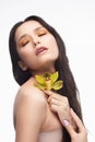 A beautiful brunette nude shoulders girl sensually holds a flower of an orchid in her hands. Nude make-up. Healthy smooth skin Royalty Free Stock Photo