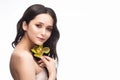 A beautiful brunette nude shoulders girl sensually holds a flower of an orchid in her hands. Nude make-up. Healthy smooth skin Royalty Free Stock Photo