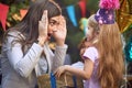 Beautiful brunette playing peek a boo with cute little blonde girl at birthday party Royalty Free Stock Photo