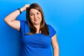 Beautiful brunette plus size woman wearing casual blue t shirt confuse and wonder about question Royalty Free Stock Photo