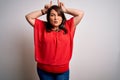 Beautiful brunette plus size woman wearing casual red t-shirt over isolated white background doing funny gesture with finger over Royalty Free Stock Photo