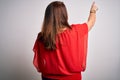 Beautiful brunette plus size woman wearing casual red t-shirt over isolated white background Posing backwards pointing ahead with Royalty Free Stock Photo