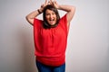 Beautiful brunette plus size woman wearing casual red t-shirt over isolated white background Posing funny and crazy with fingers Royalty Free Stock Photo